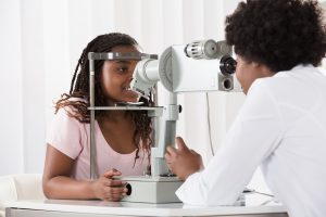 Female Optometrist Examining Patient On Phoropter In Ophthalmology Clinic